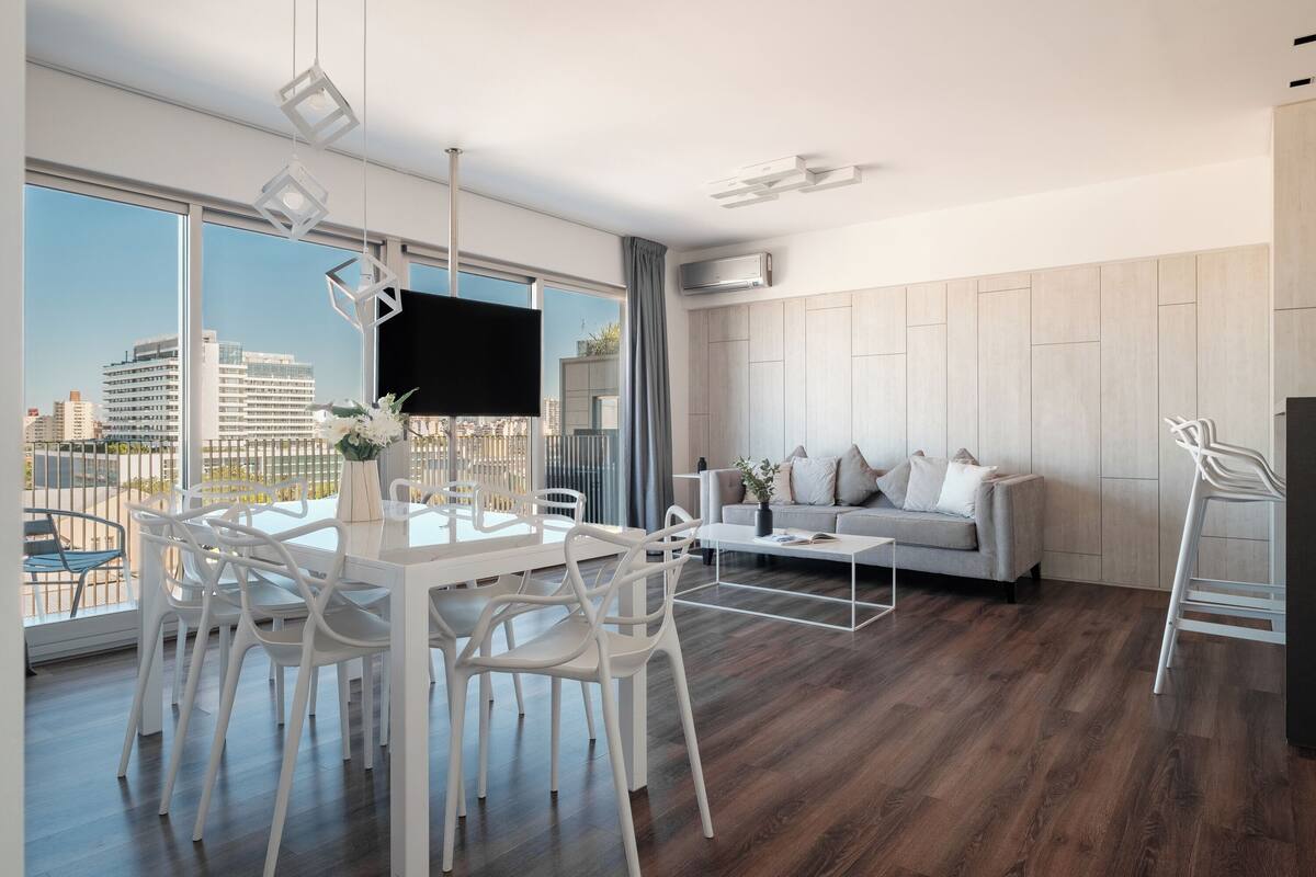 A modern living room with a dining area, a sofa, and a TV.