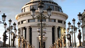 A grand building with a dome and classical columns, surrounded by ornate street lamps and statues. - Hotel Square (Skopje)