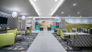 Eine Hotelhalle mit Empfangsbereich, Sitzgelegenheiten und einem großen Wandgemälde.