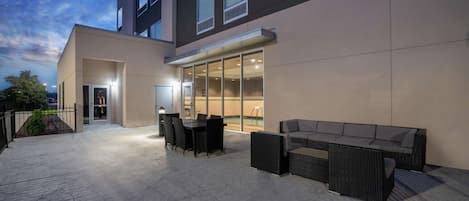 Un patio al aire libre con una mesa y sillas de comedor, un sofá y una entrada con cerramiento de vidrio.