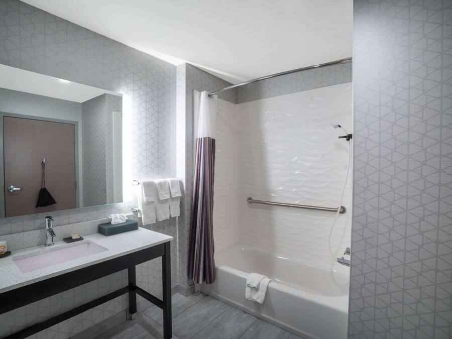 Un baño moderno con un espejo grande, un lavabo, una ducha y una bañera.