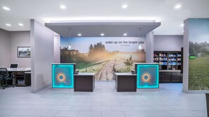 Ein Empfangsbereich mit einem großen Poster, zwei Empfangstresen, einem Laptop und einem Bücherregal.