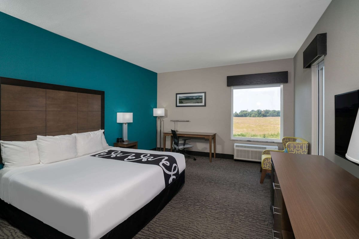 Habitación de hotel con una cama grande, un escritorio, una silla, un televisor y una ventana con vistas al exterior.