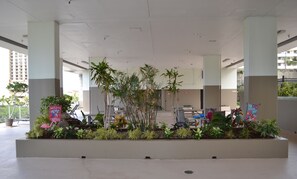 A spacious indoor area with a central planter with various plants, a welcome sign, and a few chairs. - COZY STUDIO WITH WAIKIKI, OCEAN AND DIAMOND HEAD VIEW. FREE WI-FI.   (Honolulu)