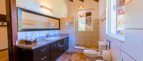 A bathroom with a double sink, a large mirror, a shower, and a toilet.