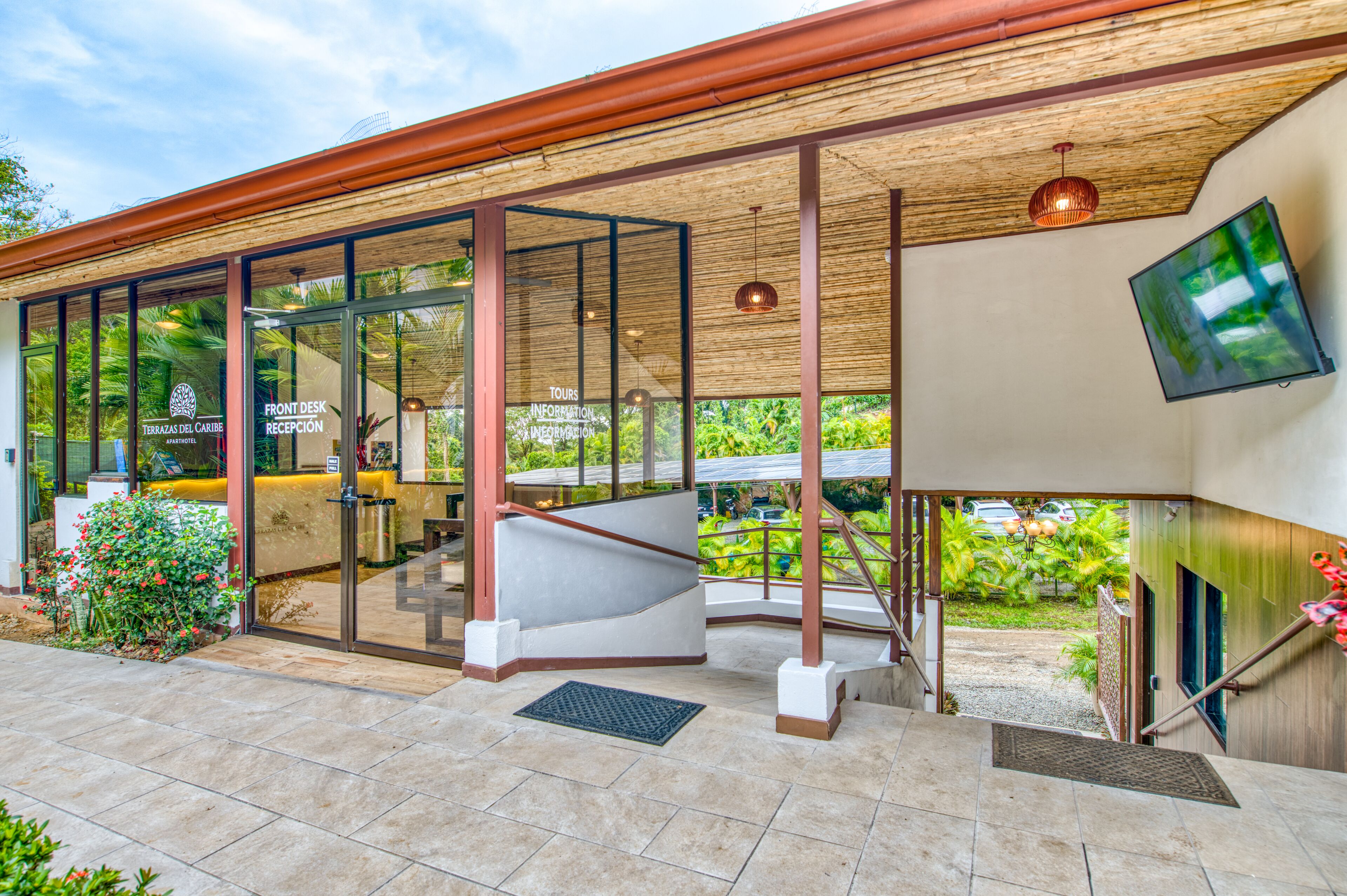 A modern hotel with a reception desk, glass doors, a staircase, and a view of the outdoors.