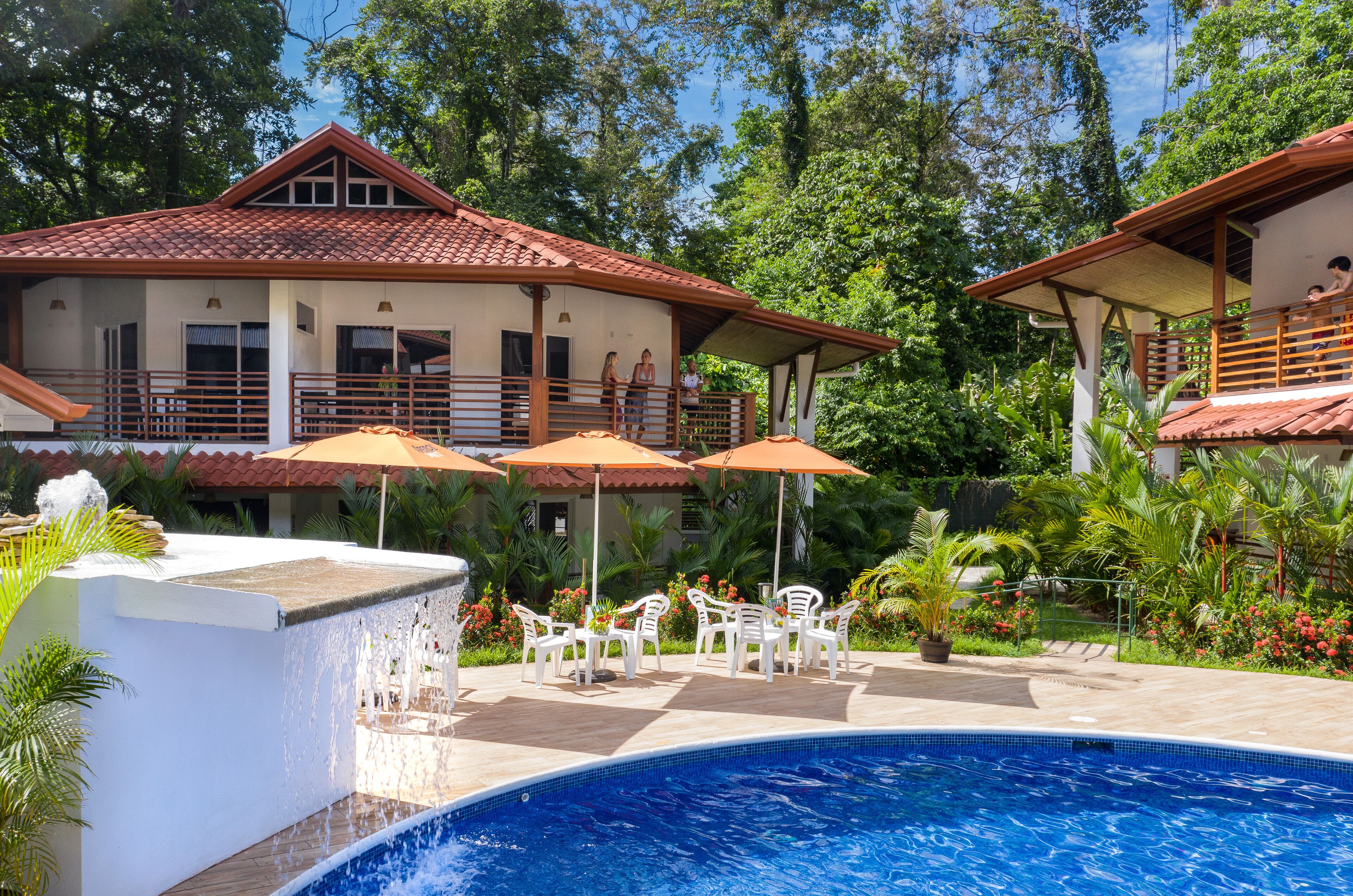 A pool area with a clear blue pool, white lounge chairs, and umbrellas.