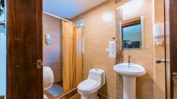 A bathroom with a toilet, shower, and sink.