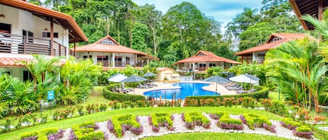 Una piscina al aire libre, sombrillas, sillones reclinables de piscina