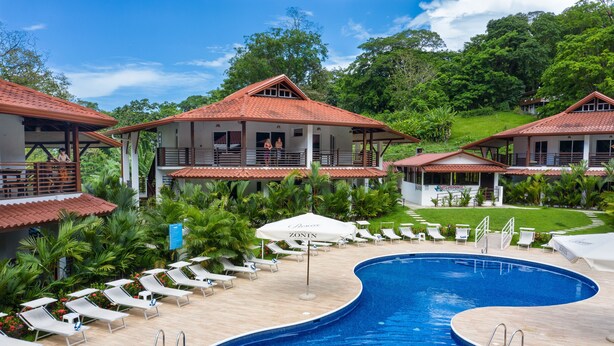 A resort with a swimming pool, lounge chairs, and a view of the surrounding greenery. - Terrazas del Caribe Hotel (Cahuita)