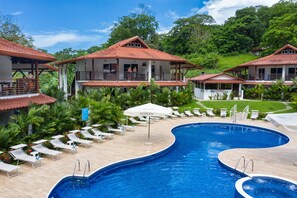 Un resort con piscina, sillas de descanso y vistas a la vegetación circundante.