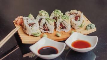 Sushi on a wooden board with two small bowls of soy sauce.