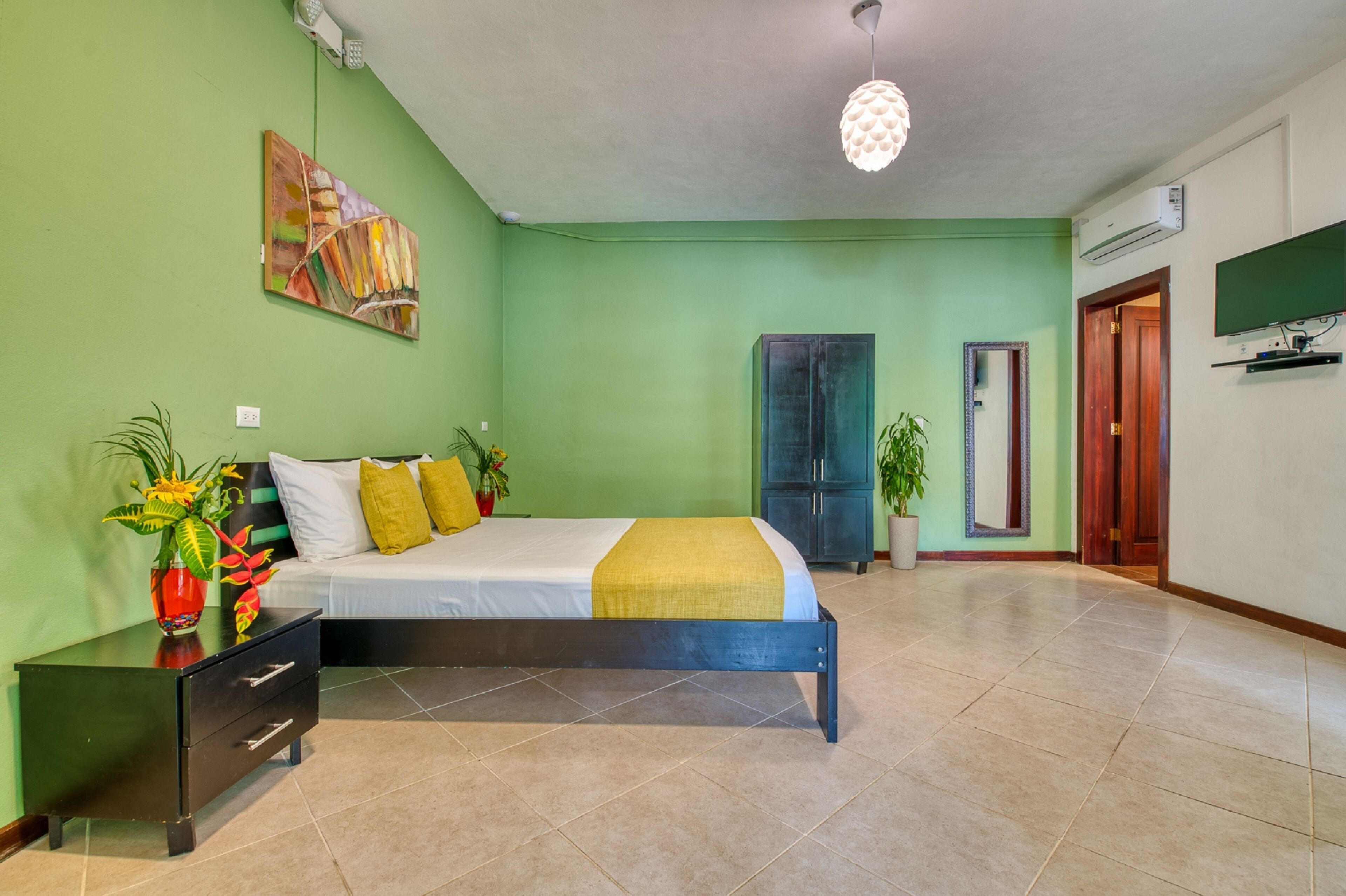 Een slaapkamer met een bed, nachtkastje en een groene wand.