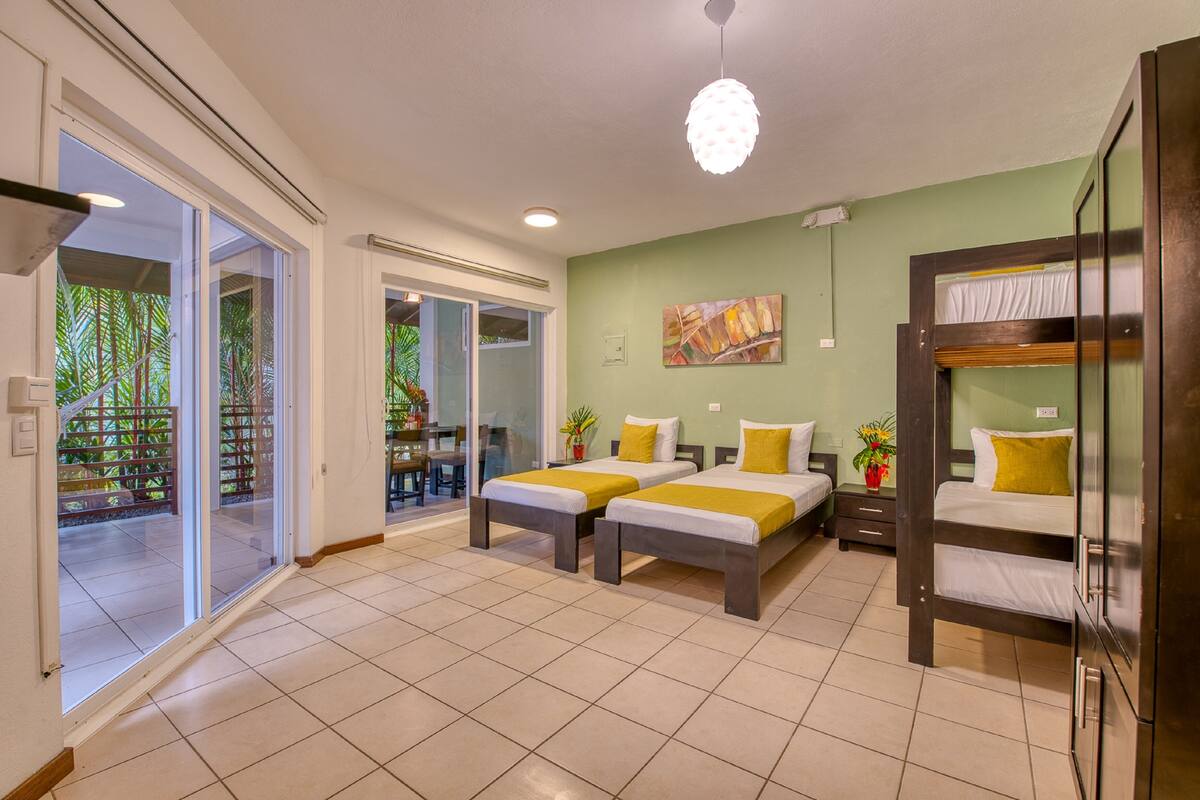 Une chambre d’hôtel avec deux lits, un balcon et une vue sur la verdure.