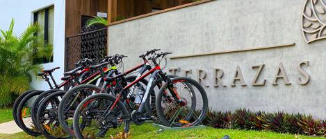Un edificio moderno con un letrero que dice "TERRAZAS" y varias bicicletas estacionadas adelante.