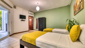 A hotel room with two beds, a TV, a wardrobe, and a green wall.