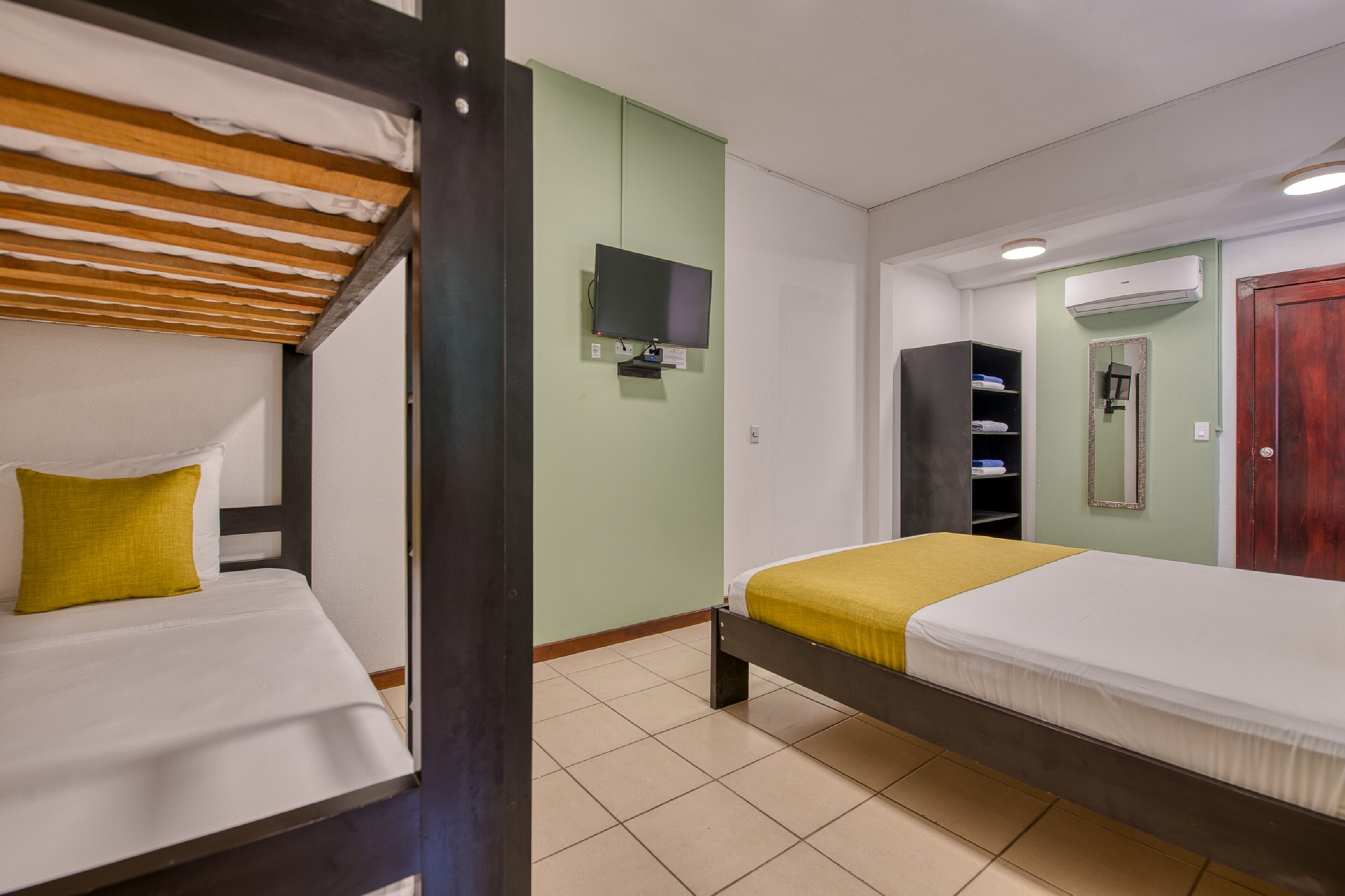 A room with two beds, a TV, a mirror, and a wardrobe.