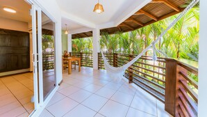 A spacious balcony with a hammock, wooden railing, and a view of lush greenery. - Terrazas del Caribe Hotel (Cahuita)