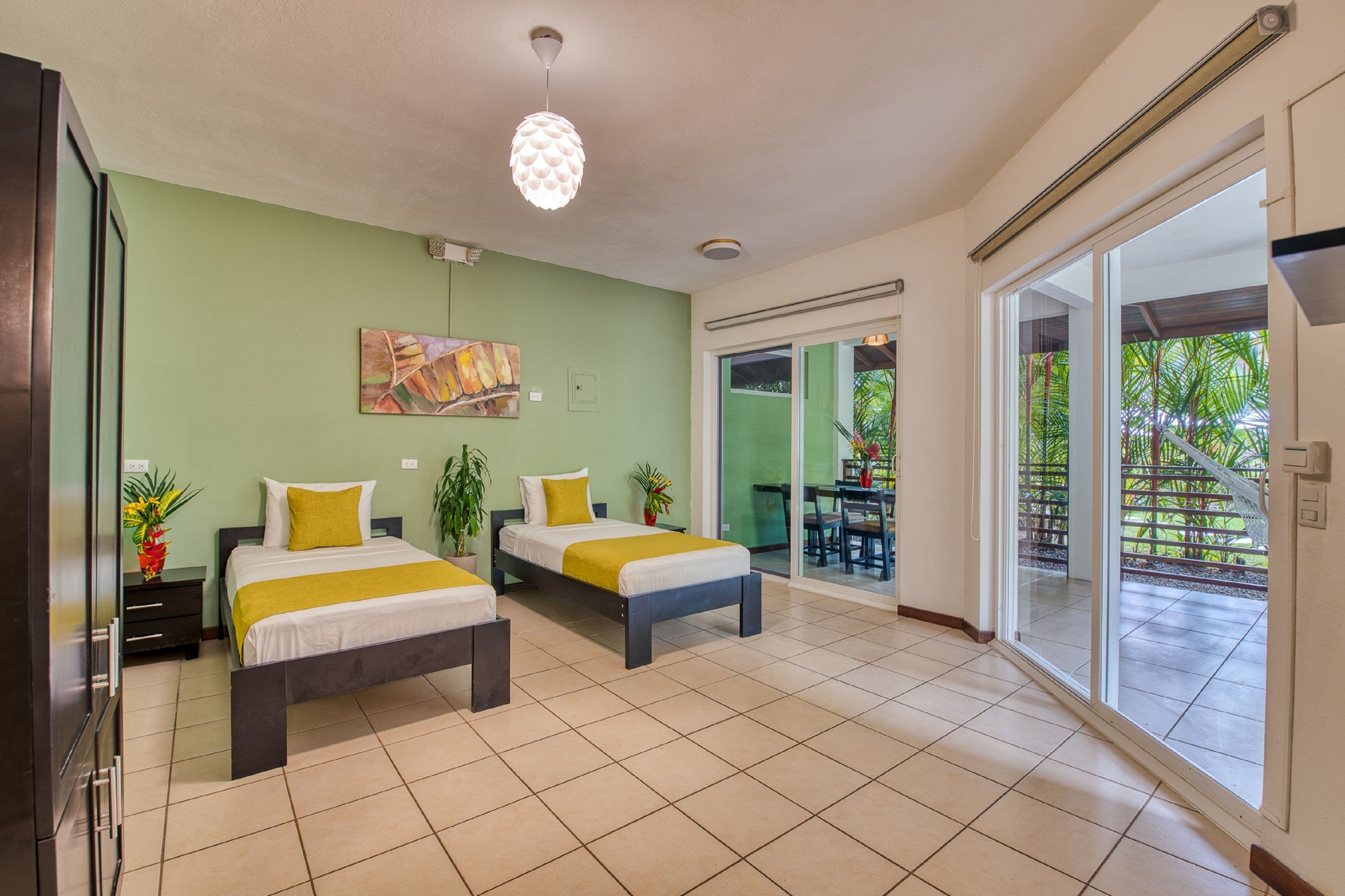 A hotel room with two beds, a dining area, and a sliding glass door to the outside.