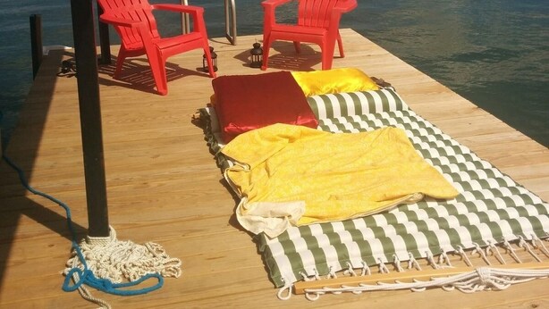 A wooden dock with two red Adirondack chairs, a yellow towel, and a green and white striped mat. - Admiral's Club, wide cove, spa, pool/ping pong/air hockey/poker tables (Gainesville)