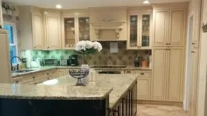 A kitchen with a large island, beige cabinets, and a tiled floor. - Admiral's Club, wide cove, spa, pool/ping pong/air hockey/poker tables (Gainesville)