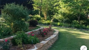 A well-maintained garden with a stone border, various shrubs, and flowering plants. - Admiral's Club, wide cove, spa, pool/ping pong/air hockey/poker tables (Gainesville)