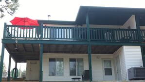 Een tweelaags huis met een balkon, een rode parasol en een overdekte patio.