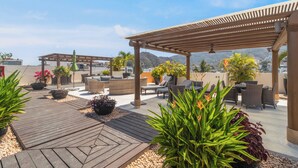 Terraza en la azotea con mobiliario exterior, plantas en macetas y una pérgola.
