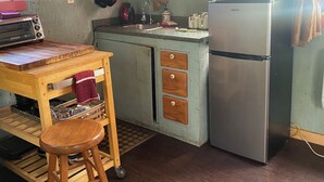 A kitchen with a wooden table, a stool, a refrigerator, a microwave, and a sink.