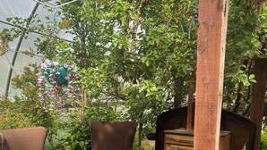 A rustic outdoor seating area with a wooden bench, two brown armchairs, and a wooden table.