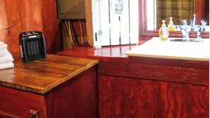 A wooden cabin bathroom with a wooden vanity, a sink, a mirror, a clock, and a small stool.