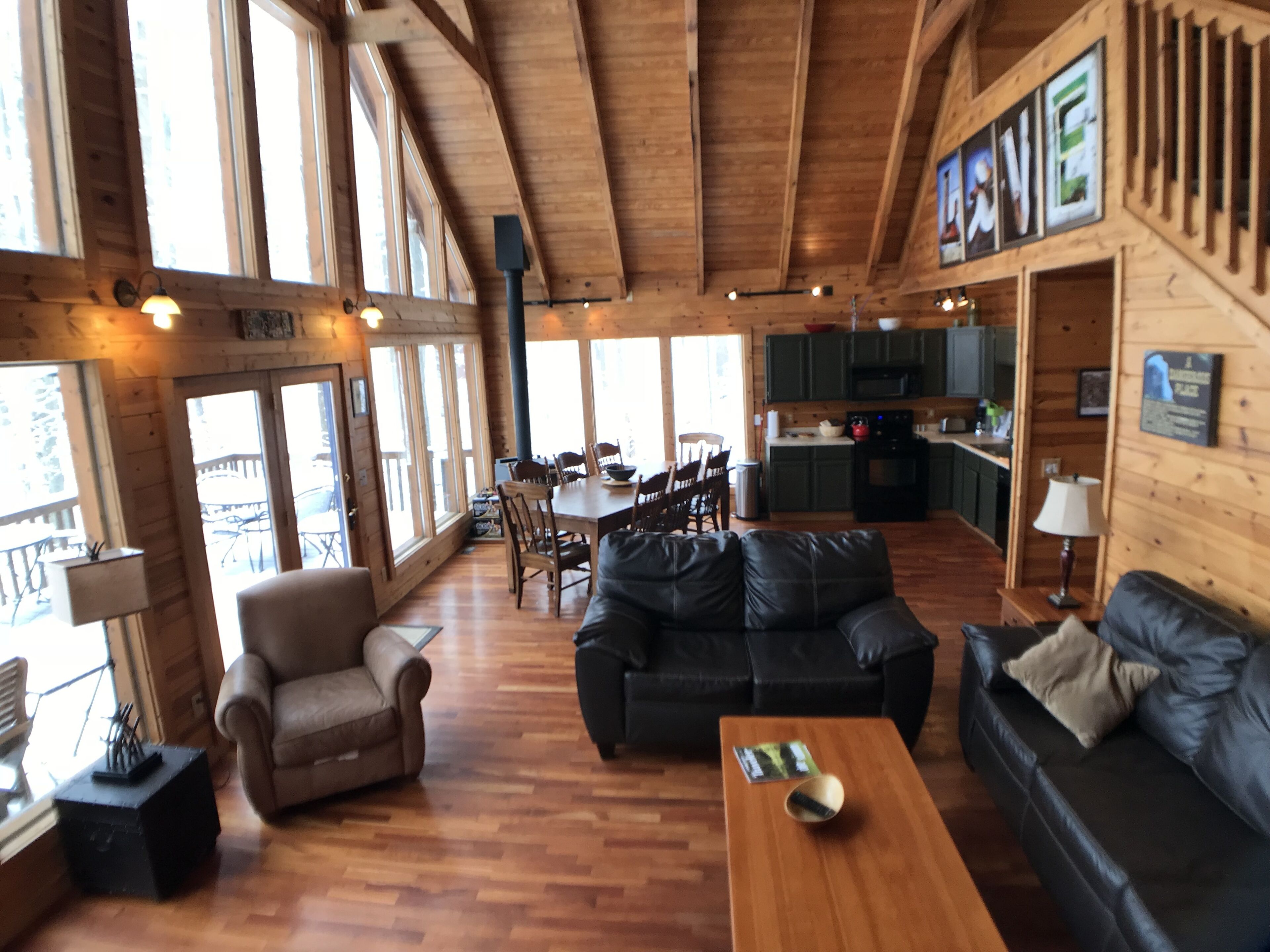 A spacious living area with a wooden ceiling, a dining table with chairs, a sofa, and a coffee table.
