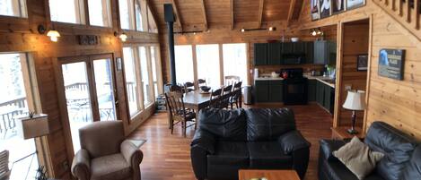 A spacious living area with a wooden ceiling, a dining table with chairs, a sofa, and a coffee table.