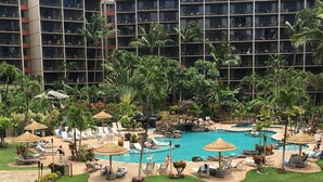 Een resort met een centraal gelegen zwembad, omringd door ligbedden en parasols, met op de achtergrond een meer verdiepingen tellend gebouw.