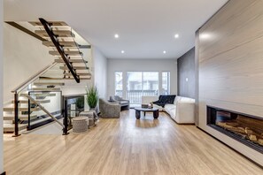 A modern living room with a staircase, a fireplace, and a large window. - Snowy Creek 15 - Ski in Ski out, Complete Luxury Renovation, Fireplace (Whistler)