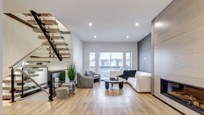 Een moderne woonkamer met een trap, een open haard en uitzicht op de stad.