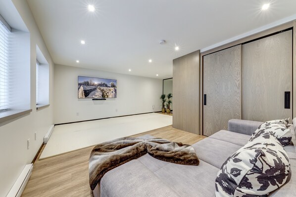 A modern bedroom with a large bed, a wooden wardrobe, a mounted TV, and a window with blinds. - Snowy Creek 15 - Ski in Ski out, Complete Luxury Renovation, Fireplace (Whistler)