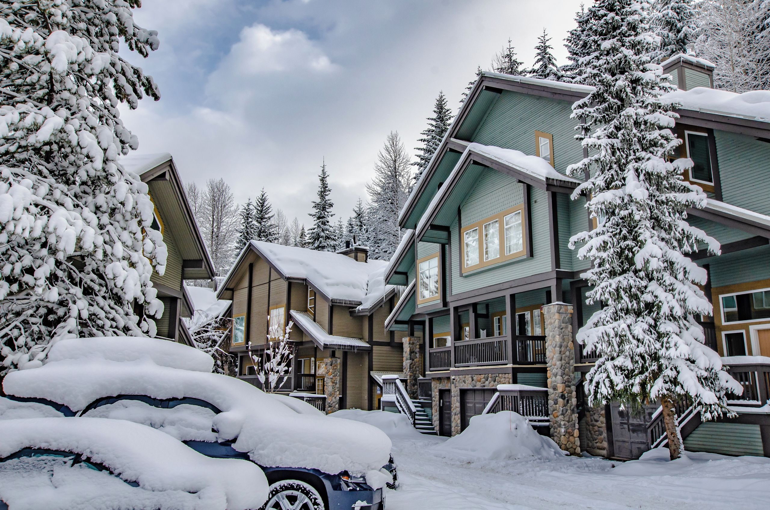 A multi-story lodge with a snow-covered exterior, a stone staircase, and a balcony.