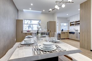 A modern kitchen with a marble countertop, built-in cabinets, and a dining area set for a meal. - Snowy Creek 15 - Ski in Ski out, Complete Luxury Renovation, Fireplace (Whistler)