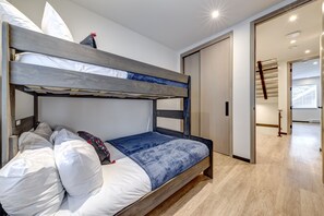 A bunk bed with white bedding and a blue patterned blanket.