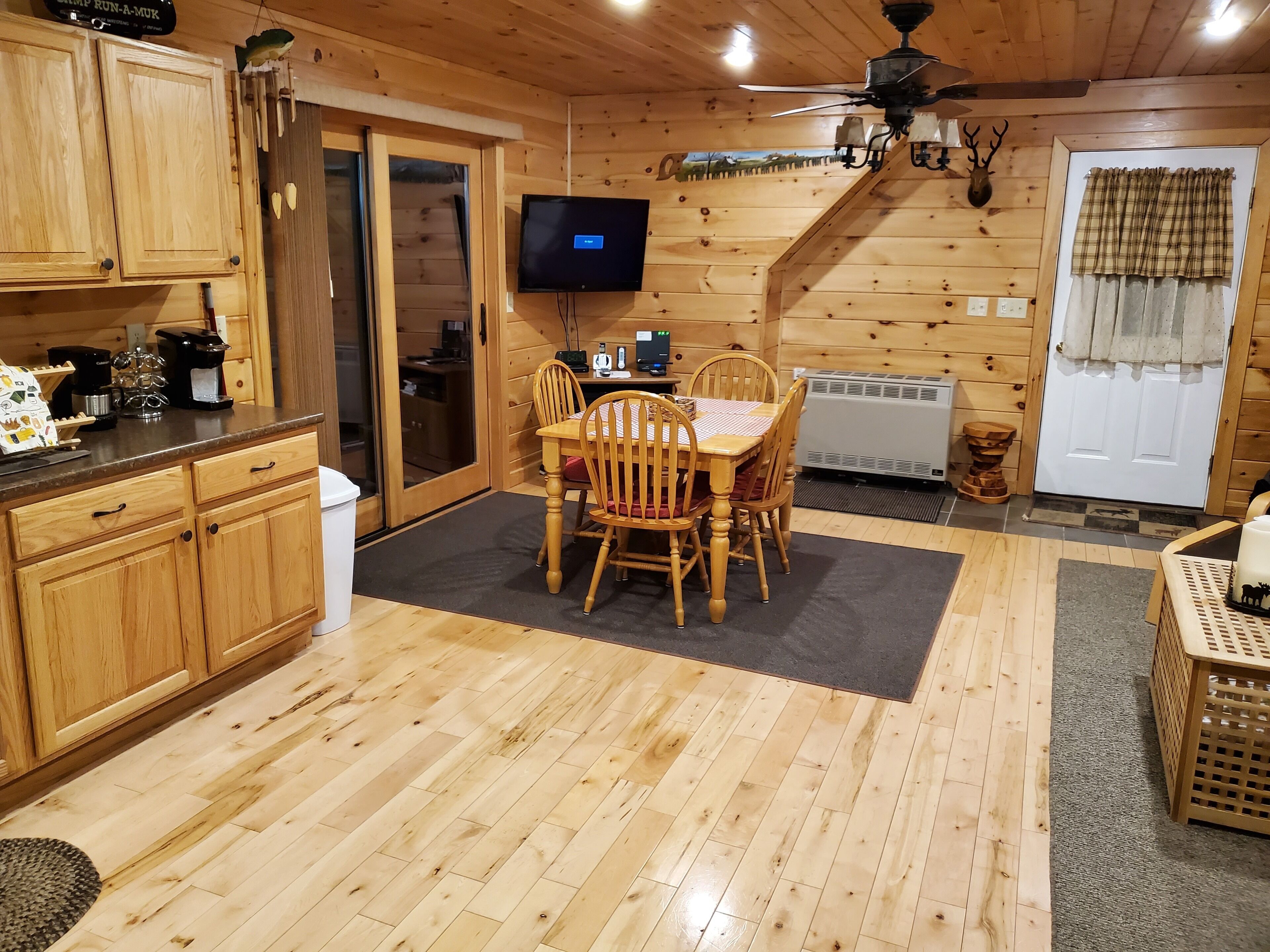 Un interior de madera con una mesa de comedor, sillas, un televisor y un ventilador de techo.