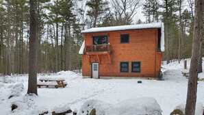 A cabin with a wooden exterior, a balcony, and a snow-covered roof. - River Front Cabin with Mountain Views (Jay)