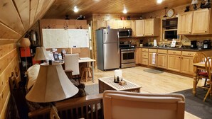 A cozy wooden cabin interior with a dining area, kitchen, and a small table with a lamp. - River Front Cabin with Mountain Views (Jay)