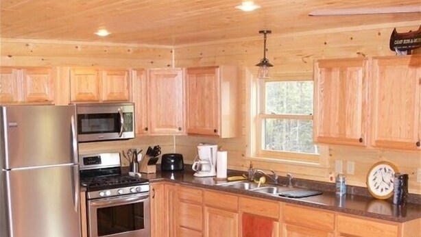 A wooden cabin kitchen with a refrigerator, microwave, stove, and sink. - River Front Cabin with Mountain Views (Jay)