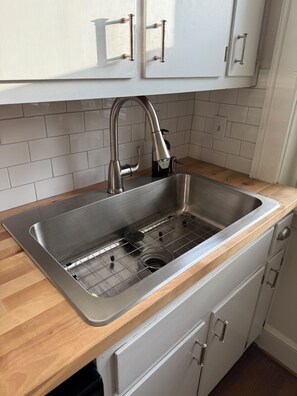 Ein Edelstahl-Spülbecken mit modernem Wasserhahn, einer Seifenspender und einem Siebgitter.