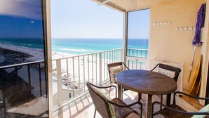 Un balcon avec une table et des chaises, donnant sur une plage et l’océan.