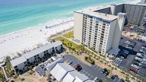Un hôtel de grande hauteur offrant une vue sur la plage, avec un espace de stationnement et une piscine.