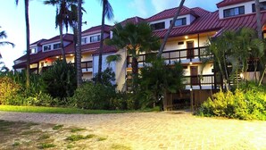 A hotel with multiple floors, balconies, and palm trees. - Gorgeous boho at the beach walkout oceanfront condo in Sapphire D building. (St Thomas)