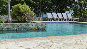 Una piscina con sillas de descanso y un muro de piedra.