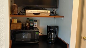 A compact kitchenette with a flat-screen TV, a microwave, a coffee maker, and a small refrigerator.